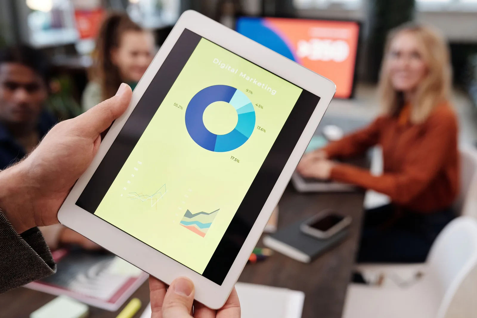 Business team reviewing digital marketing statistics on a tablet during an indoor meeting. B2B content marketing checklist: the items people skip