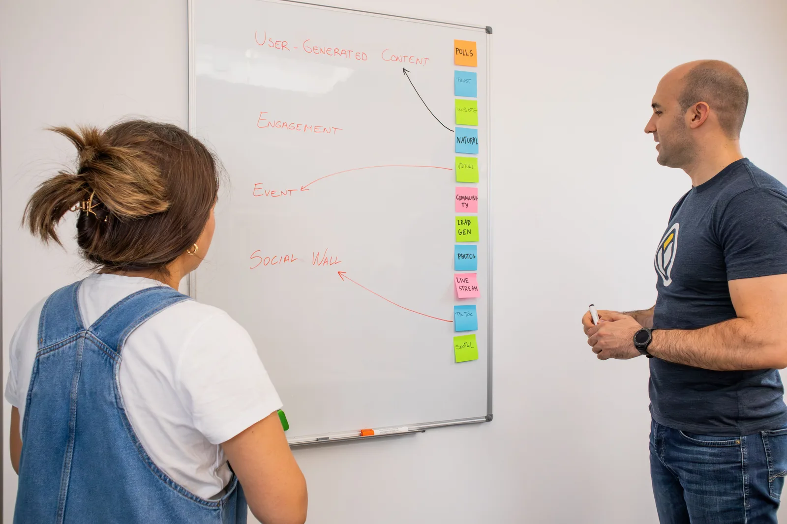 Two colleagues collaborate on a marketing strategy at a whiteboard in a modern office setting. B2B content marketing mistakes that experienced operators still make