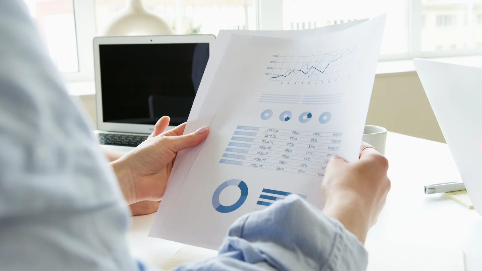 Close-up of a person analyzing business charts and graphs indoors. Reading B2B SaaS benchmark ranges for 2027 marketing decisions